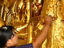 Ritual gold leaf appllication on a Buddha image of Shwedagon Pagoda in Yangon